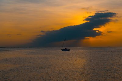 Silhouette sailboat in sea against sky during sunset