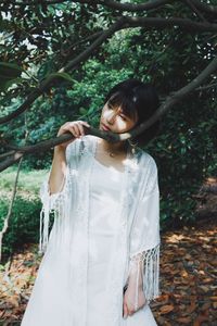 Young woman standing by tree