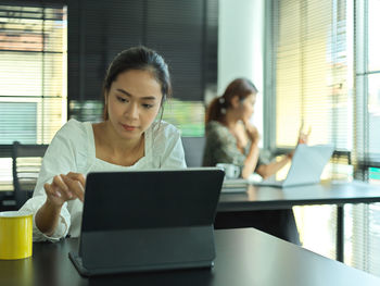 Young woman using mobile phone while sitting on table