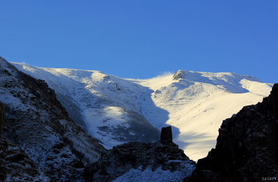 Scenic view of snowcapped mountains against clear blue sky