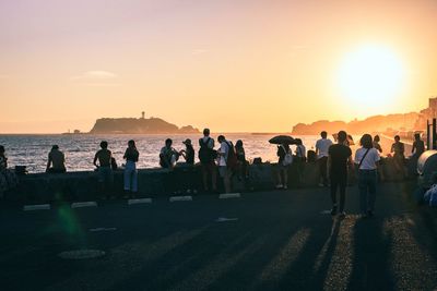 People on beach against sky during sunset
