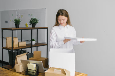 A cute girl opens a large white document box next to her laptop