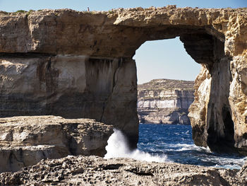 Rock formations by sea against sky