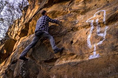 Low angle view of young man climbing on rock