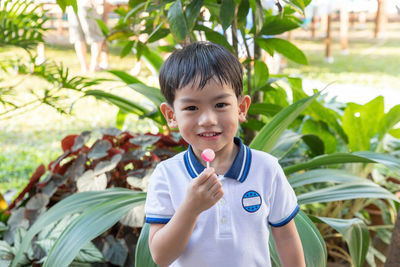 Portrait of boy eating lollipop in park