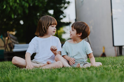 Side view of mother and daughter sitting on field