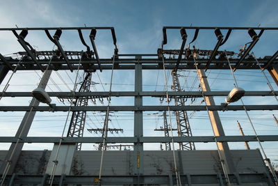 Low angle view of crane by building against sky