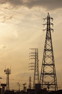 Low angle view of electricity pylon against sky during sunset