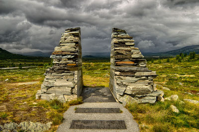 Stone wall on landscape against sky