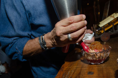 Midsection of man holding ice cream on table