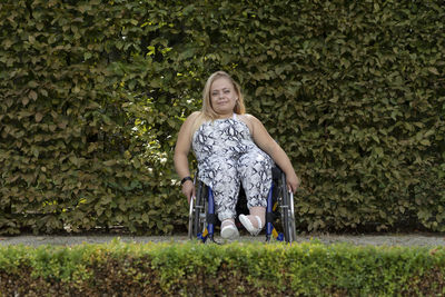 Portrait of young woman standing against plants