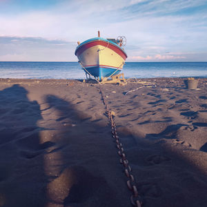 Fish boat on beach against sky