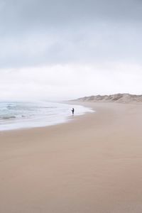 Man standing at beach against sky