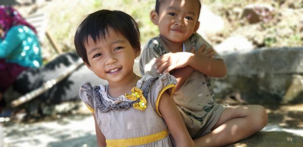 Portrait of siblings smiling on footpath