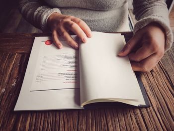 Midsection of person reading book on table