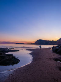 Sunset coastal colourful reflections with woman looking into the distance