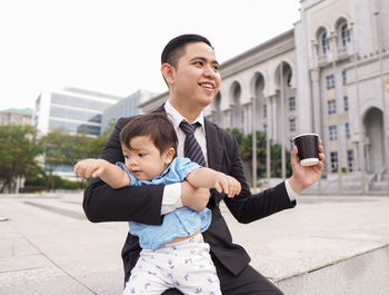 Full length of father holding baby in city