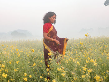 Side view of young woman sitting on field