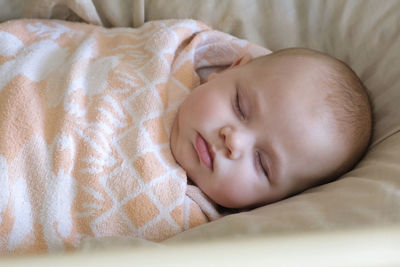 Safe sleep for baby, swaddle. adorable newborn sleeping swaddled in bed. swaddling for infants. 