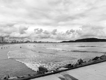 View of calm beach against cloudy sky