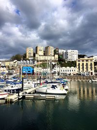 Boats in sea against cloudy sky