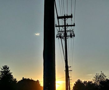 Low angle view of silhouette electricity pylon against sky