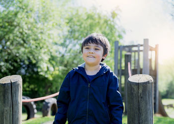 Portrait of boy standing on wooden post