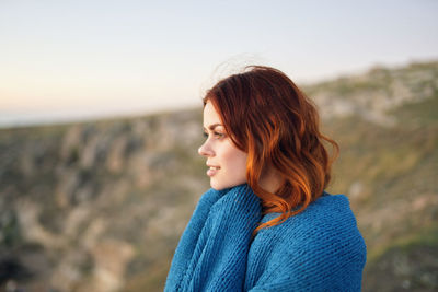 Portrait of young woman looking away against sky