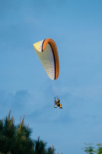 Low angle view of person powered paragliding in sky