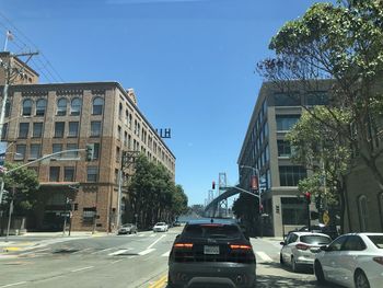 Cars on road amidst buildings against clear sky