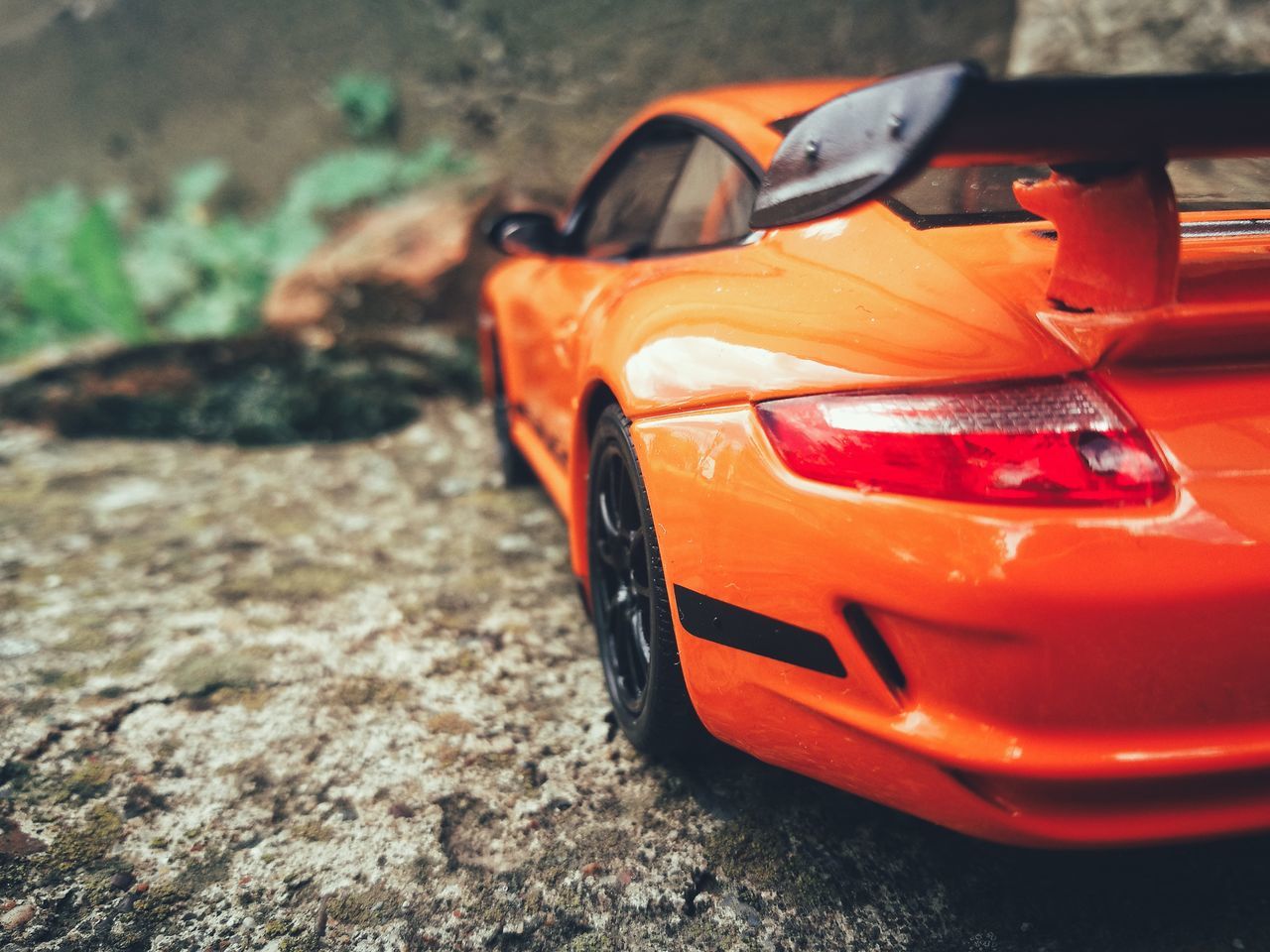 mode of transportation, orange color, car, motor vehicle, land vehicle, transportation, close-up, focus on foreground, day, no people, stationary, toy car, red, toy, outdoors, plastic, high angle view, city, selective focus, travel