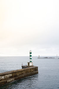 Lighthouse by sea against sky