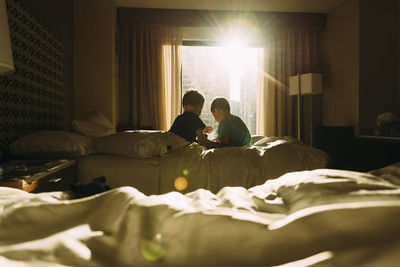 Rear view of boys on bed at home