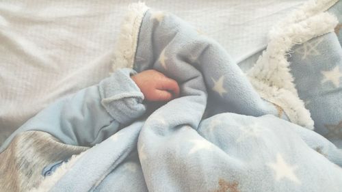 Cropped image of baby sleeping on bed