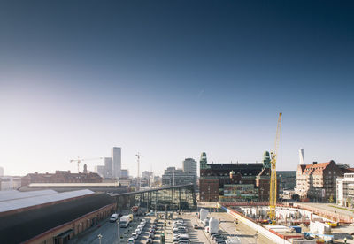 High angle view of parking lot by buildings against clear blue sky