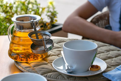 Mug, a cup and a brewed teapot with fruit tea on the table of a roadside cafe