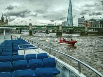 Boats in river against cloudy sky
