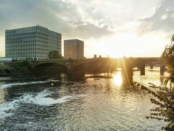 Sunset over river with buildings in background