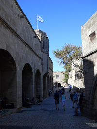 People walking in historic building against sky