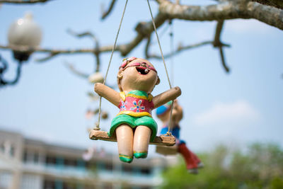 Low angle view doll hanging on swing against sky