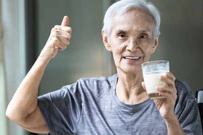 Portrait of senior woman gesturing while drinking milk