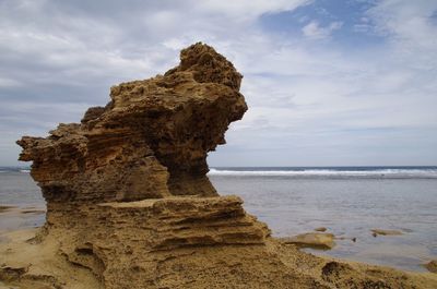 Rock formation on beach against sky