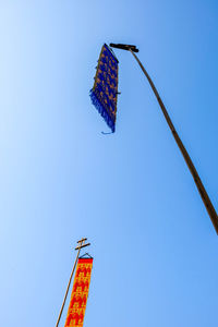 Low angle view of flags against clear blue sky