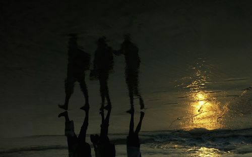 Silhouette trees by sea against sky during sunset