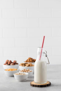 A bottle of vegetable milk on the background of bowls with nuts, oat flakes. 