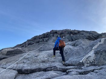 Full length of woman on rock against blue sky