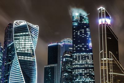 Low angle view of illuminated cityscape against sky at night