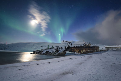 Scenic view of snow covered land against sky at night