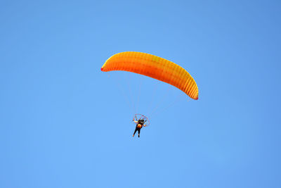 Low angle view of person paragliding against clear blue sky