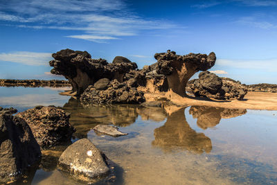 Rock formation in sea against sky